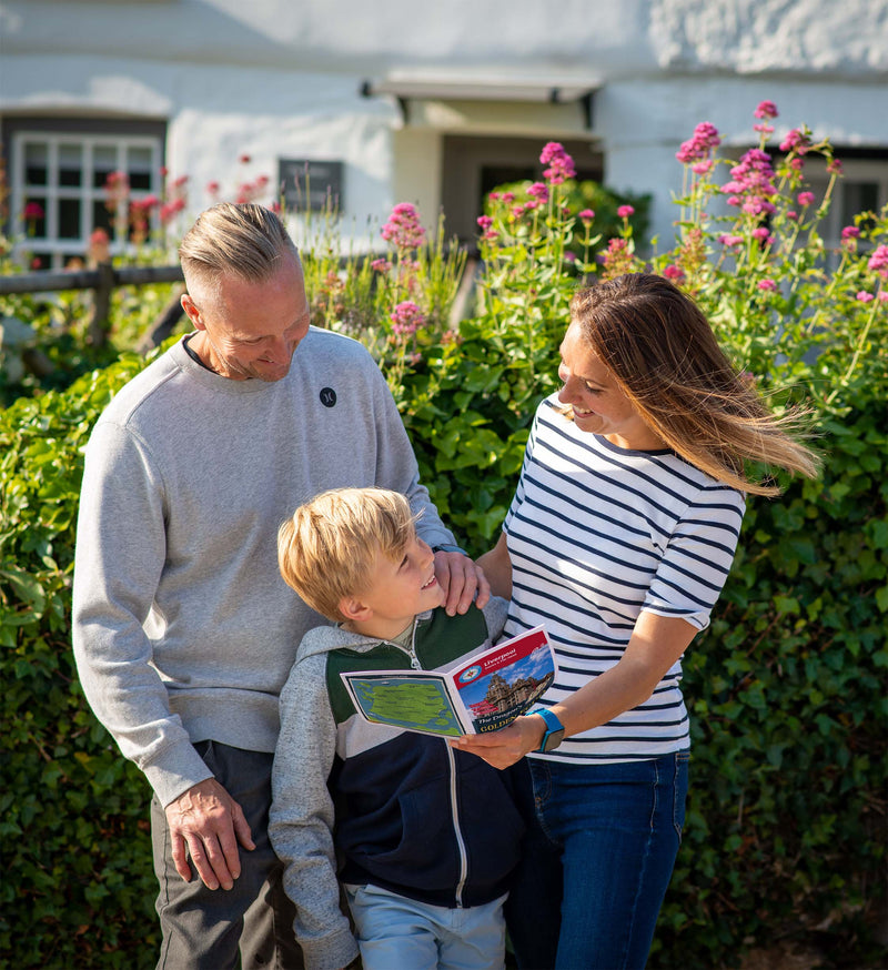 A family reading a Treasure Trails booklet together on a sunny street