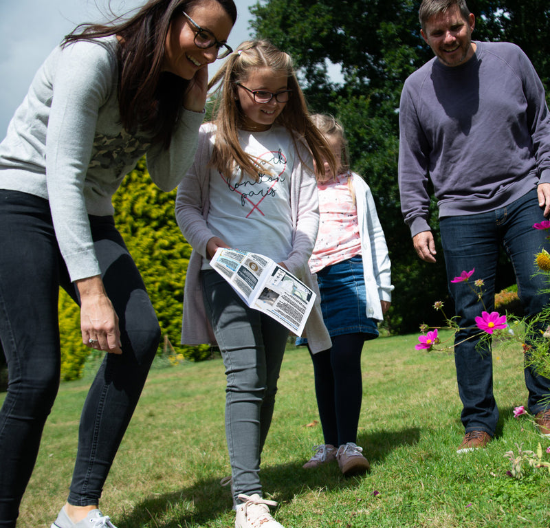 A family reading a Treasure Trails booklet together on a sunny street